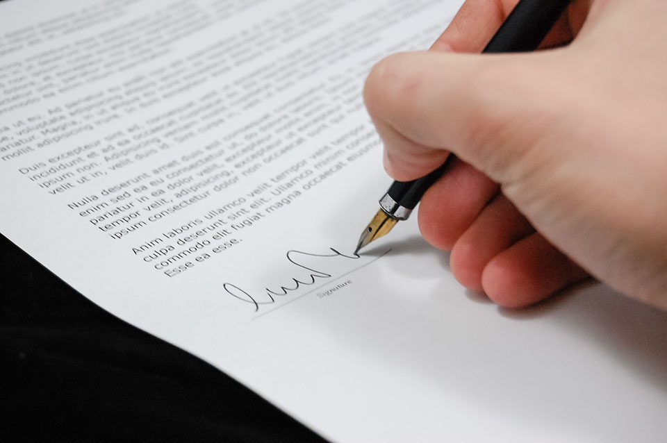 a person's hand seen signing a document
