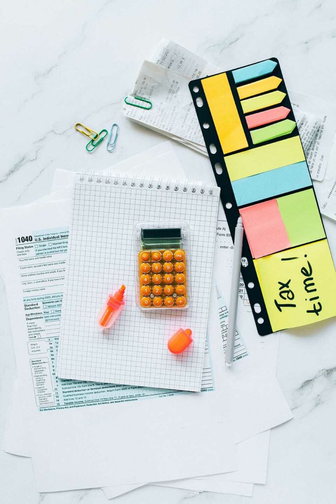 A desk with a calculator, pen, paper, and stickers to prepare taxes